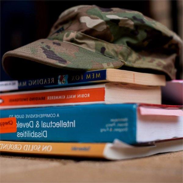 camouflage hat with brim atop a stack of books